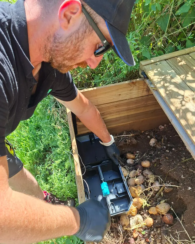Technicien Derateam 3D ganté posant un poste d'appâtage sécurisé dans un jardin