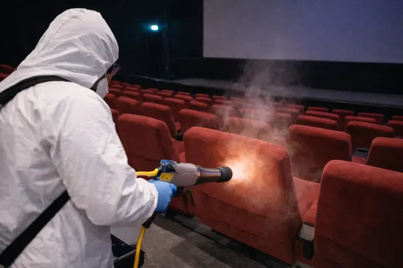 Technicien traitant à la vapeur les fauteuils d'une salle de cinéma