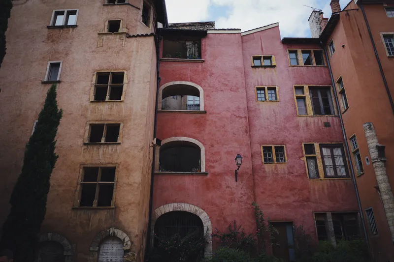 Cour intérieure d'immeubles anciens aux façades ocre et rose, fenêtres en arcades