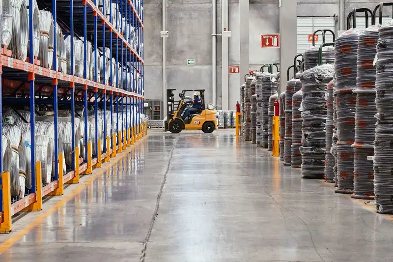 Allée d'entrepôt logistique, rayonnages métalliques, chariot élévateur et marchandises empilées