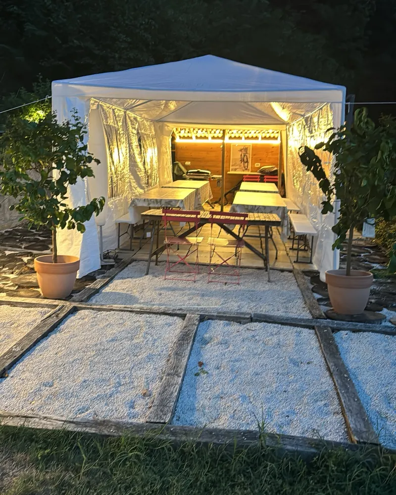 Barnum éclairé à la tombée de la nuit, tables et bancs dressés pour un événement en plein air